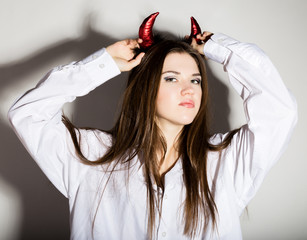 young girl in a man's white shirt with red horns looks like pretty Devil