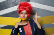 © Artur Novak - Retrato de chica joven con estética punk y post-punk (tribu urbana futurista) con peluca roja y con la cara pintada haciendo gestos provocativos