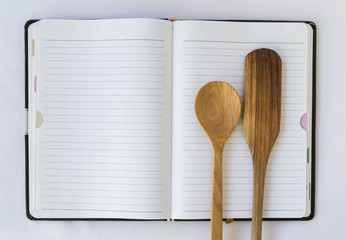 Wall Mural - Wooden spoon on blank notebook on white background