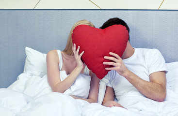 Poster - happy couple in bed with red heart shape pillow