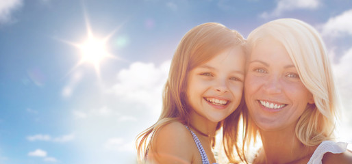 Wall Mural - happy mother and child girl over sun in blue sky