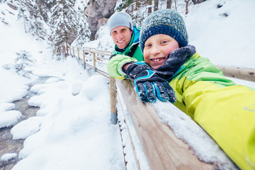 Wall Mural - Boy takes self photo with his father on winter walk in mountain