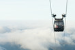 Cable car cabin going up above the clouds to the very top of a mountain at a ski resort area