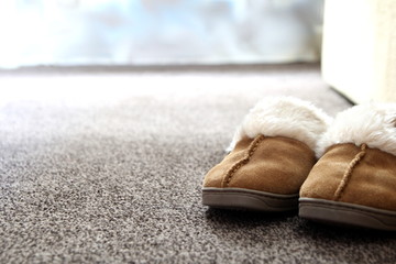 Generic ladies suede slippers on carpet next to sofa in a nice l