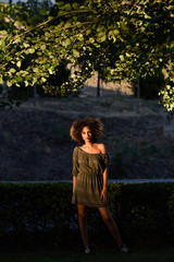 Wall Mural - Young black woman with afro hairstyle smiling in urban backgroun