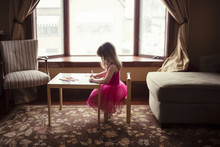Side View Of Girl Drawing At Table In Living Room