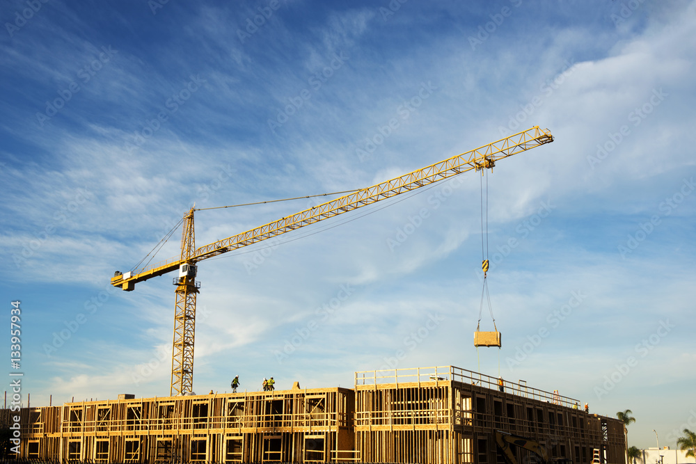 Crane at construction site against cloudy sky Stock Photo | Adobe Stock