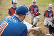 © Cavan Images - Coach pointing while discussing with baseball team on field