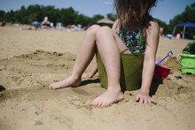 Girl Sitting In Bucket At Beach