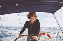 Mature Woman Driving Boat On Sea Against Sky