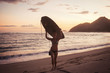 © Cavan Images - Female surfer carrying surfboard on head at beach during sunset