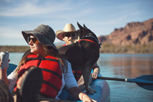 Friends With Dog Sitting In Inflatable Kayak On Lake