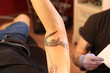 © Africa Studio - Freshly inked alligator tattoo on forearm, tattoo artist working on new design, body art and personal expression