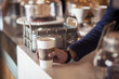 © Cavan Images - Cropped image of barista holding disposable cup at counter in cafe