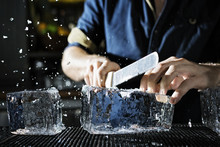 Midsection Of Chef Breaking Ice Block In Kitchen