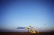 © Cavan Images - Oil pumps on field against blue sky