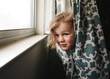 © Cavan Images - Playful girl peeking while hiding in curtain