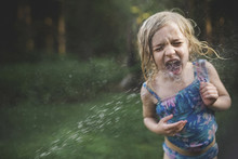 Girl Enjoying In Water Spray At Backyard