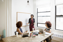 Confident Businesswoman Explaining Strategy To Female Colleagues In Board Room