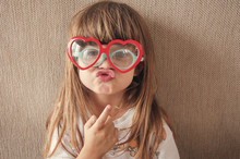 Portrait Of Girl Wearing Novelty Glasses While Puckering Against Wall