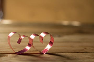 Ribbons shaped as hearts on wood background, valentine day conce