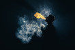The man smoke an electronic cigarette against the background of bright light