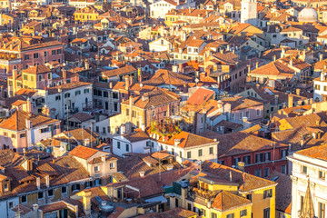 Wall Mural - Aerial view of Venice, Italy, at sunset with rooftops of building, the sea and warm sunlight.