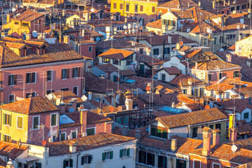 Wall Mural - Aerial view of Venice, Italy, at sunset with rooftops of building, the sea and warm sunlight.