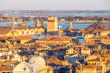 Wall Mural - Aerial view of Venice, Italy, at sunset with rooftops of building, the sea and warm sunlight.