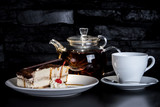 Fototapeta  - Delicious tiramisu dessert with a cup of tea on a wooden table. Traditional sweet dessert.