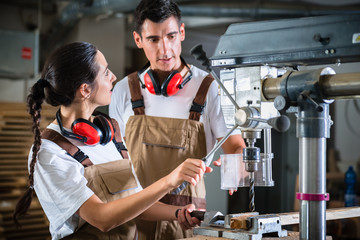 Wall Mural - Carpenter woman and man with drill in workshop