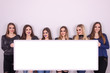 © focusandblur - Group of young girls holding a big white board and looking at th