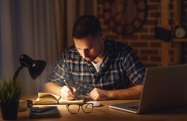 man working on computer at home at night in dark .