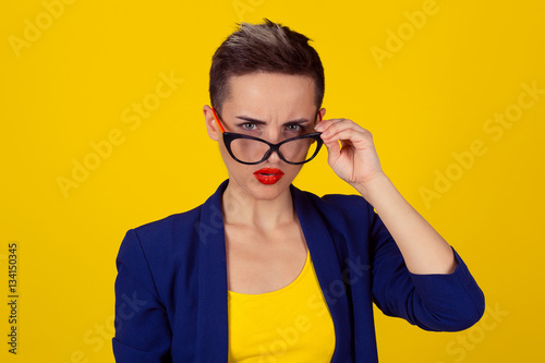 Fotografía Closeup portrait beautiful young business woman lady looking at you camera over glasses gesture skeptically isolated yellow background