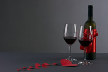 Wine Bottle And Two Wineglasses With Red Hearts On A Gray Background. Love Card Concept With Copy Space, Valentine's Day Theme