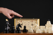 Hand Pushing Chess Time Clock. Playing Quick Chess With Timer On Dark Background