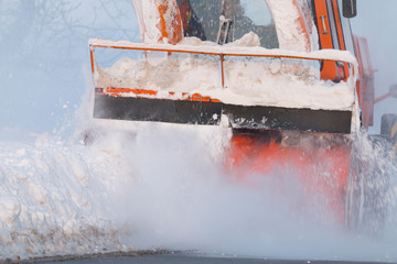 Snow truck cleaning snow from the road and streets working at sunset light on snowy day