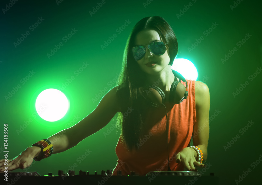 Pretty young DJ playing music in nightclub