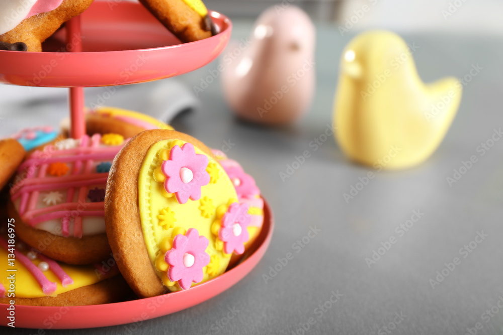 Stand with colourful Easter cookies on kitchen table, closeup