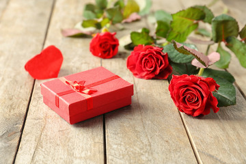 Poster - St. Valentines Day concept. Fresh red roses and gift box on wooden table