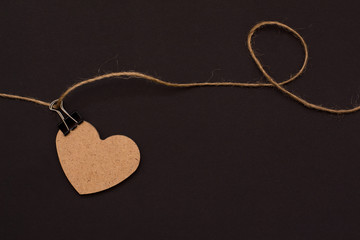 heart of wood on a rope with clothespin on a black background