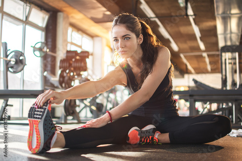 Fotomural Flexible young woman stretching her right leg in gym.
