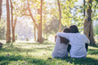 © sarawutnam - Valentine couple sit on grass in garden while sunset.