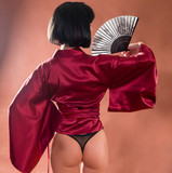 sexy geisha in Japanese red kimono with a fan. Back view female