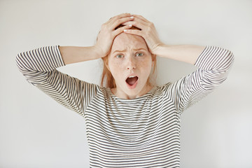 Human face expressions and emotions. Isolated headshot of student girl looking desperate and panic, holding hands on her head, screaming with mouth wide open while being late for job interview