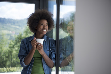 African American woman drinking coffee looking out the window