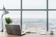 © undrey - Workplace with notebook laptop Comfortable work table in office windows and city view.