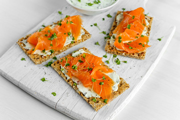 Wall Mural - Homemade Crispbread toast with Smoked Salmon, Melted Cheese and cress salad. on white wooden board