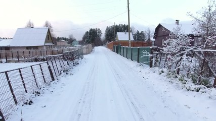 Wall Mural - Camera moving on wintry rural road among timber houses and plots of land. Winter in Russia
