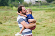 © o_lypa - Father holds his son at the hands face-to-face on a nature. Son hugging his father.